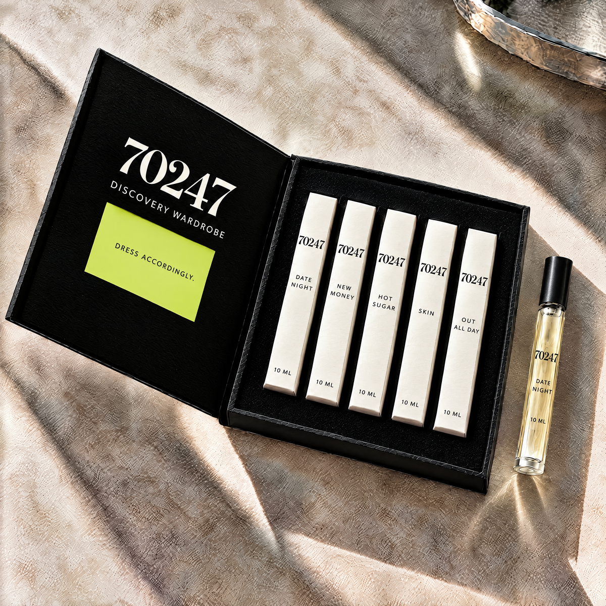 70247 Discovery Wardrobe: five individually boxed 10 ml fragrances in alabaster cartons inside a noir book-opening box, with a Date Night travel spray and lime accent.